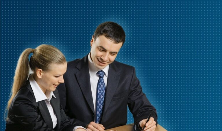 Man and woman smiling, discussing documents on desk