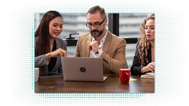 Colleagues having discussion, pointing at laptop on desk