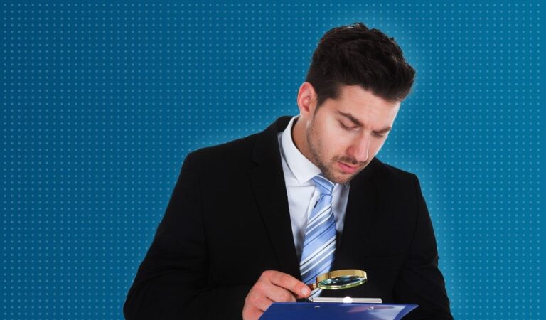 Man inspecting documents with magnifying glass