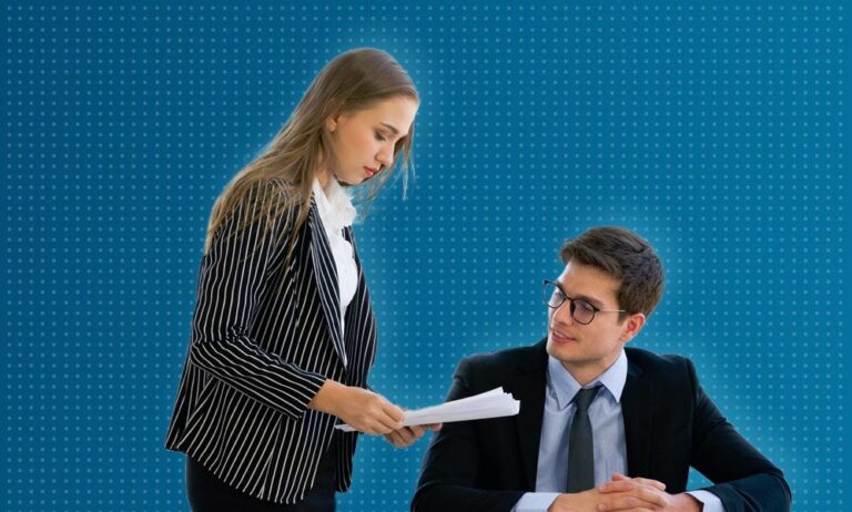 Two colleagues discussing a document over a desk