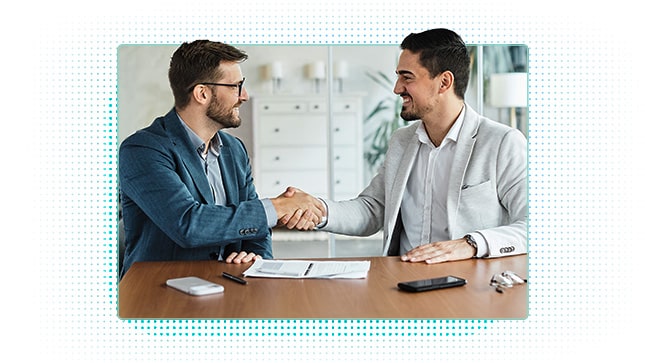 Male co-workers shaking hands over document on desk